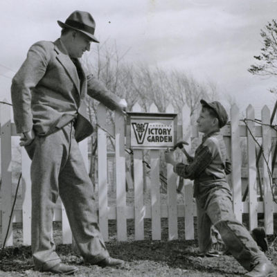 A Man And Boy Stand Next To A Picket Fence Labeled 